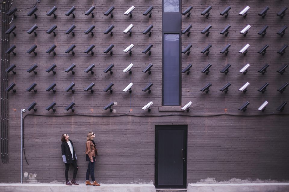 Many CCTV cameras point at two women by a building entrance