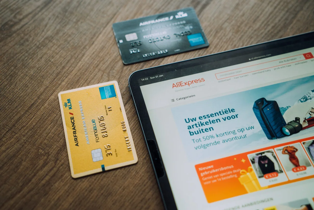 AliExpress product page on a tablet beside two payment cards